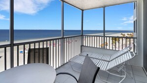 Un balcone con vista sulla spiaggia, un tavolo e una sedia.