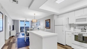 Una cucina moderna con mobili bianchi, un'isola centrale e vista all'esterno.