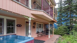 Ein zweistöckiges Gebäude mit Balkon, Whirlpool und einer Terrasse mit Gartenmöbeln.