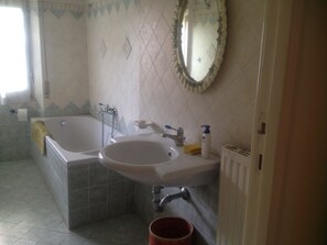 A bathroom with a bathtub, a sink, and a mirror.
