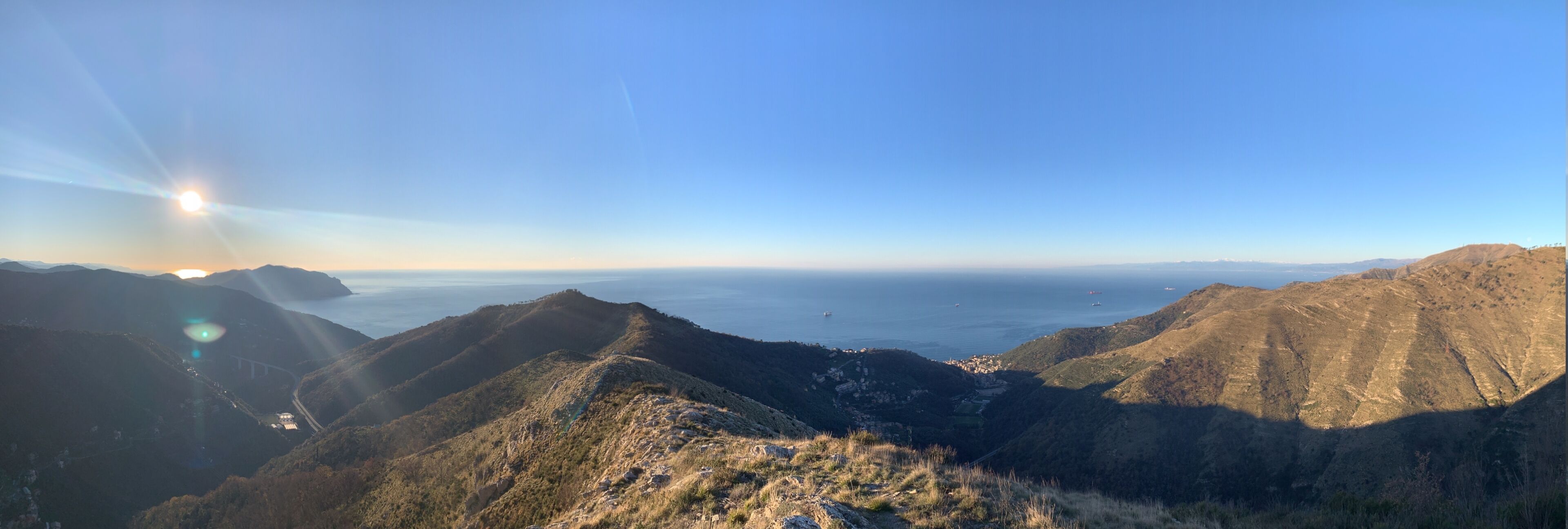 Een bergachtig landschap met een helder uitzicht op de zee en een klein dorpje in de vallei.