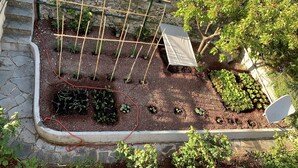 A garden with raised beds, a wooden bench, and a white chair. - Bubo House Sea View (Poggio Favaro-San Bernardo)