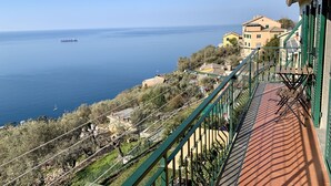 A coastal view with a balcony overlooking the sea, a building with a green railing, and a ship in the distance. - Bubo House Sea View (Poggio Favaro-San Bernardo)