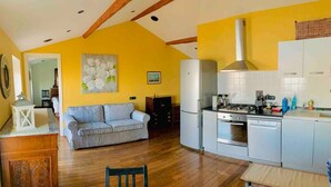 A compact kitchen with a dining area, a sofa, and a wooden cabinet. - Bubo House Sea View (Poggio Favaro-San Bernardo)