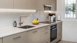 Une cuisine moderne dotée d’un grand îlot central, d’appareils électroménagers en acier inoxydable et d’une fenêtre donnant sur un paysage verdoyant.