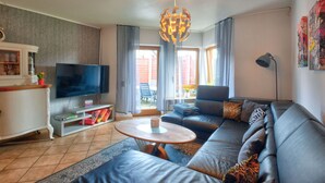 A modern living room with a sofa, television, and a dining area. - Lovely apartment for 4 people with WIFI, TV, terrace and pets allowed (Brakel)