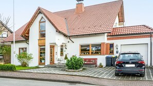 A two-story house with a red-tiled roof, a garage, and a parked black car. - Lovely apartment for 4 people with WIFI, TV, terrace and pets allowed (Brakel)