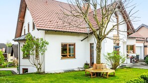 A two-story house with a red-tiled roof, a small front yard with a bench, and a tree. - Lovely apartment for 4 people with WIFI, TV, terrace and pets allowed (Brakel)