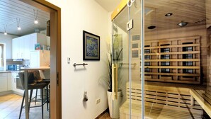 A modern kitchen with white cabinets, a microwave, and a dining area with a chair. - Lovely apartment for 4 people with WIFI, TV, terrace and pets allowed (Brakel)