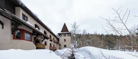 A building with a sloped roof and a small tower, surrounded by snow and trees.