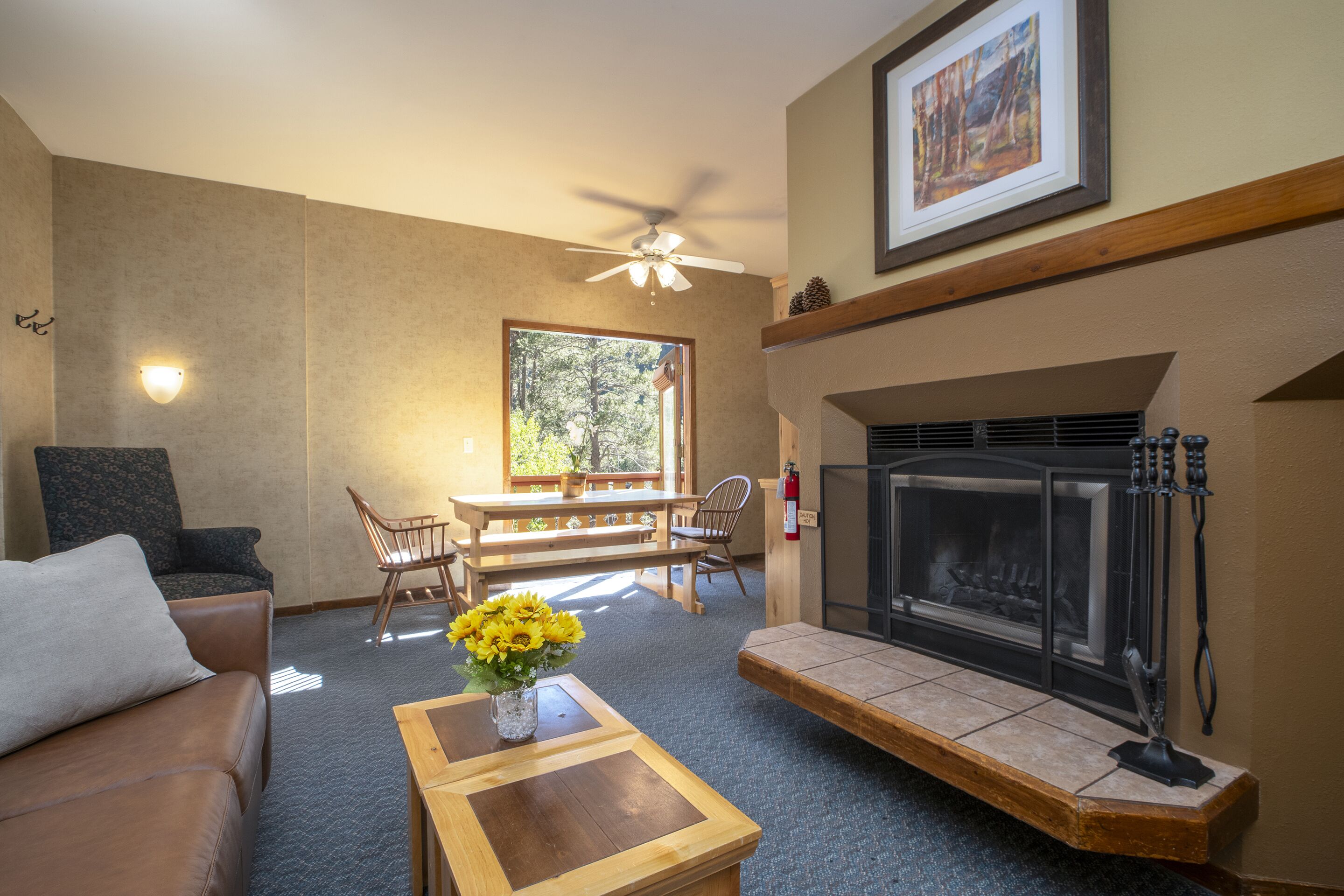 A living room with a fireplace, a ceiling fan, a dining table with chairs, and a sofa.
