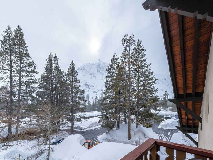 Un paysage de montagne enneigé avec un chalet en bois et un sentier recouvert de neige.