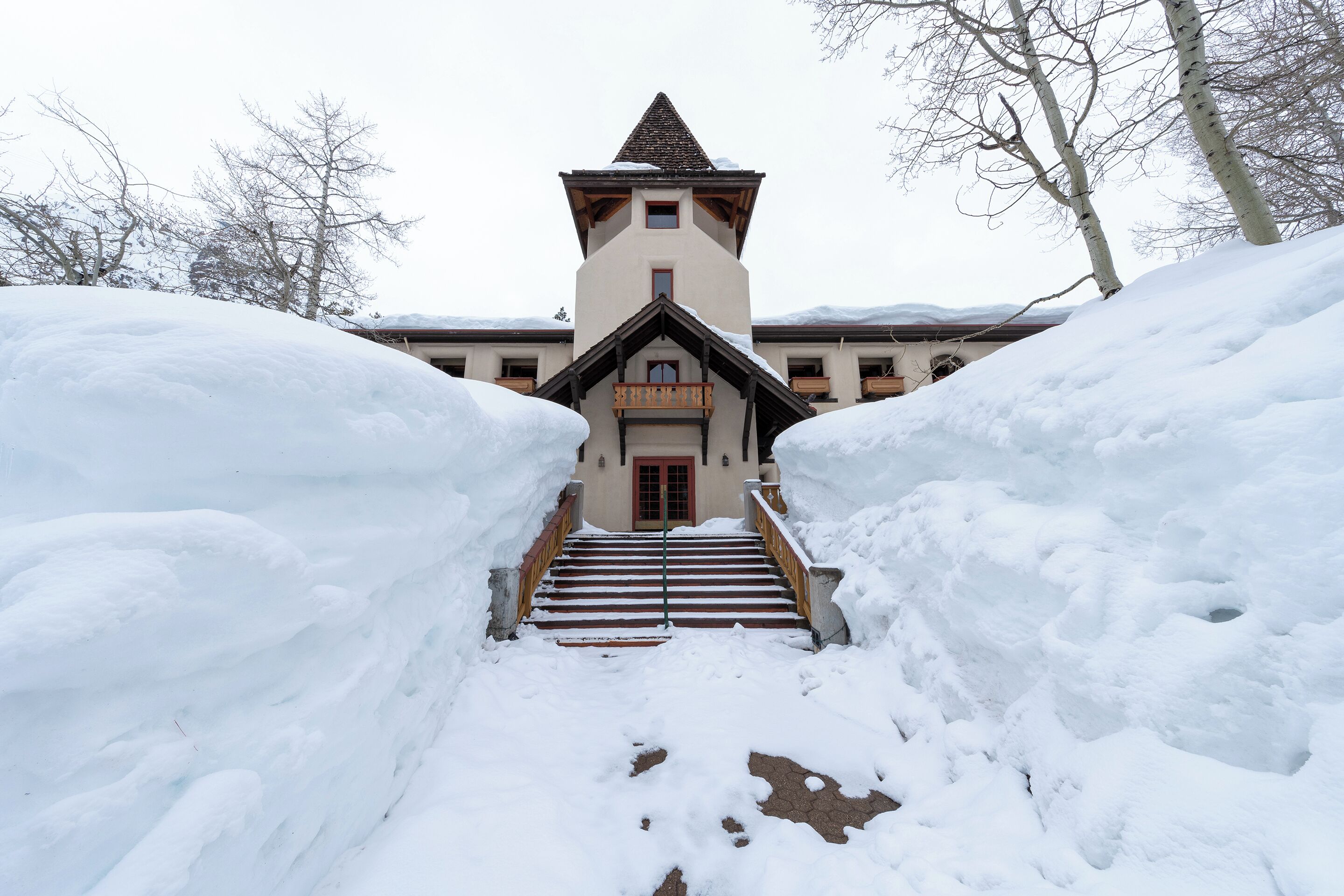 Eine schneebedeckte Treppe führt zu einem Gebäude mit einem Turm und einer roten Tür.