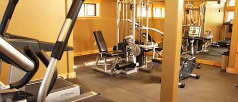 A gym with treadmills, weight machines, and a mirrored wall.