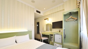 Ein Hotelzimmer mit Bett, Schreibtisch, Stuhl, Kleiderschrank und Spiegel.