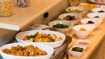 A buffet with various dishes including pasta, salads, and other food items.
