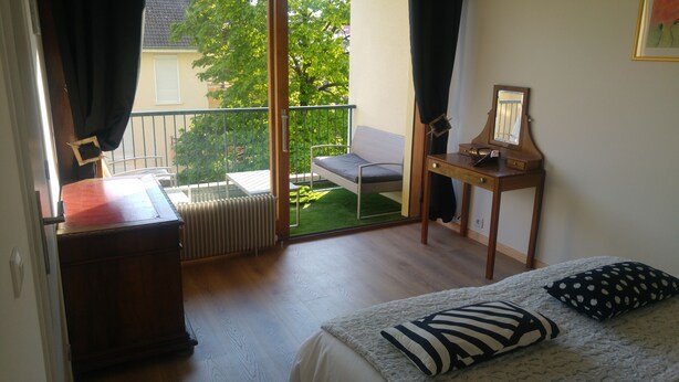 A bedroom with a bed, a wooden desk, a radiator, and a balcony with a chair and table. - Two rooms in Thonon les Bains (Thonon-les-Bains)