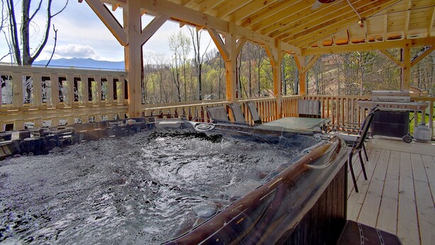 Un bain à remous avec une terrasse en bois et une vue sur les arbres.