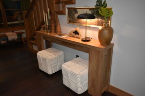 Ein Holzkonsolentisch mit Lampe, einem gerahmten Bild und einer Pflanze in einer Vase.
