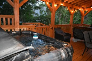 Ein Whirlpool auf einer Holzterrasse mit Blick auf Bäume.