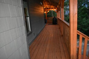 Eine Holzterrasse mit Geländer, ein überdachter Balkon und Lichterketten.