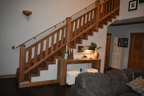 Un escalier en bois avec une console au bas, un canapé gris et une plante fixée au mur.