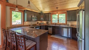 Une cuisine spacieuse dotée de meubles en bois, d’un îlot en granit et d’appareils électroménagers en acier inoxydable.