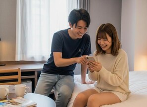 A room with a bed, a table with two cups, and a person sitting on the bed. - Business Inn Norte 2 (Sapporo)