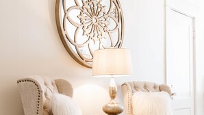 Une pièce comprenant deux fauteuils rembourrés, une table ronde avec une lampe et un élément décoratif mural.