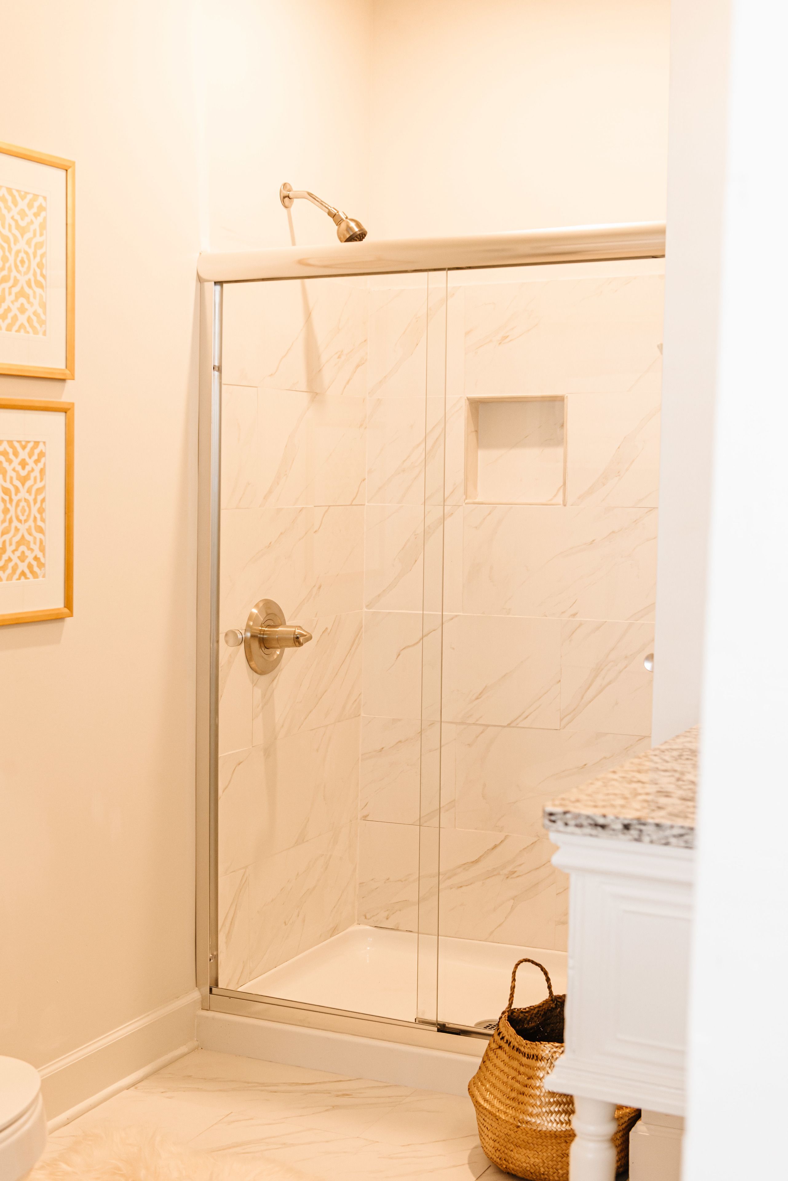 A bathroom with a glass-enclosed shower, a white toilet, and a framed picture on the wall.