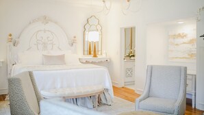 Une chambre à coucher avec un grand lit, une chaise longue, un miroir et un lustre.