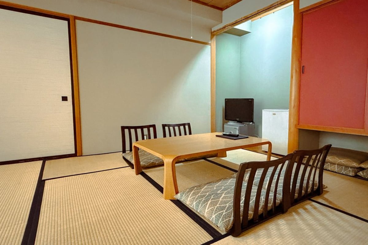 Een traditionele Japanse kamer met tatami vloeren, een lage tafel en een televisie.