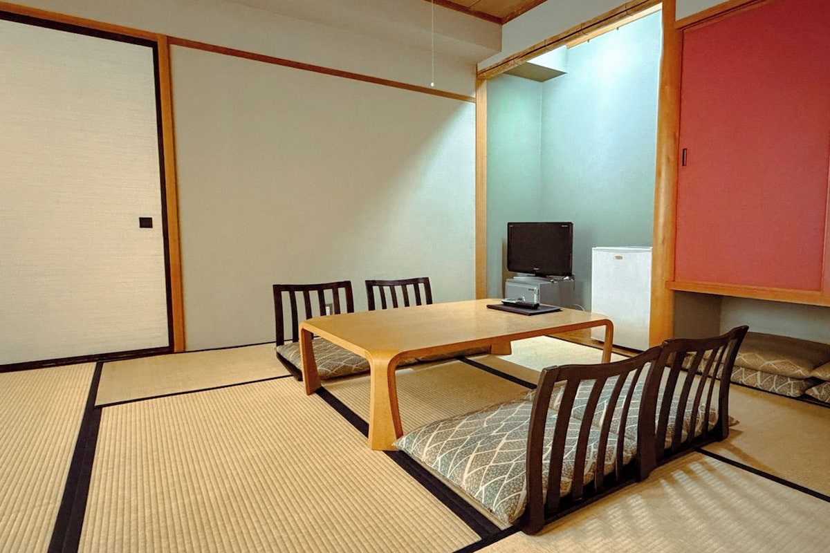 Een traditionele Japanse kamer met tatami vloeren, een lage tafel en een televisie.