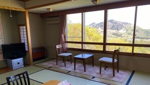 Una habitación con esteras de tatami, un televisor, una mesa y sillas.