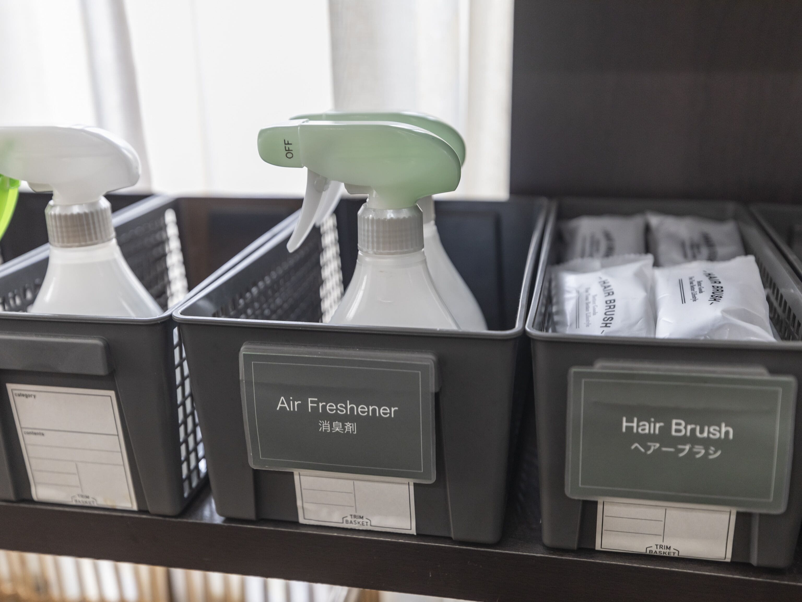 Un estante con recipientes etiquetados que contienen ambientador y cepillos para el cabello.