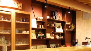 Una zona de bar con estantes de madera, sillas y una barra.