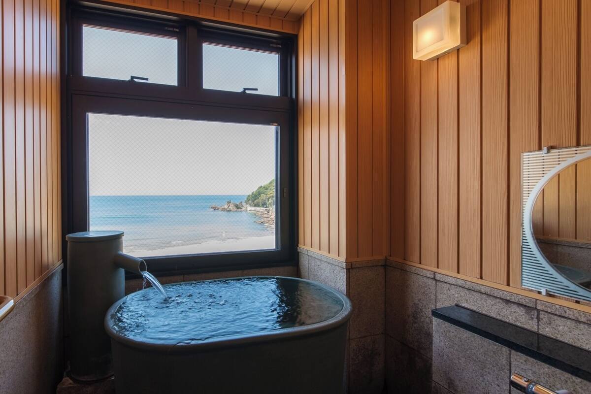 A bathroom with a large window, a bathtub, and a shower.