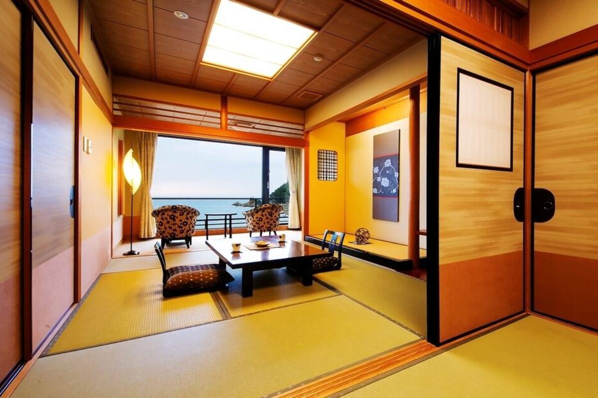 A traditional Japanese room with tatami flooring, a low table with cushions, and sliding doors.
