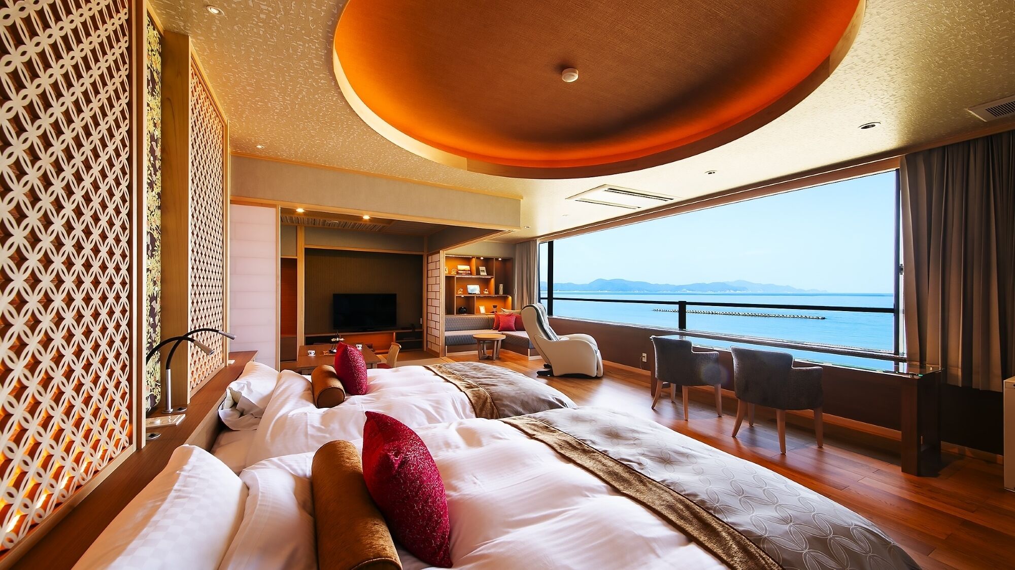 Une chambre d’hôtel dotée d’un grand lit, d’un coin salon avec un téléviseur et d’une vue sur la mer.