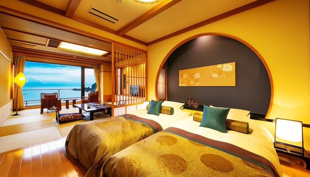 Une chambre dotée d’un grand lit, d’un bureau et offrant une vue sur la mer.