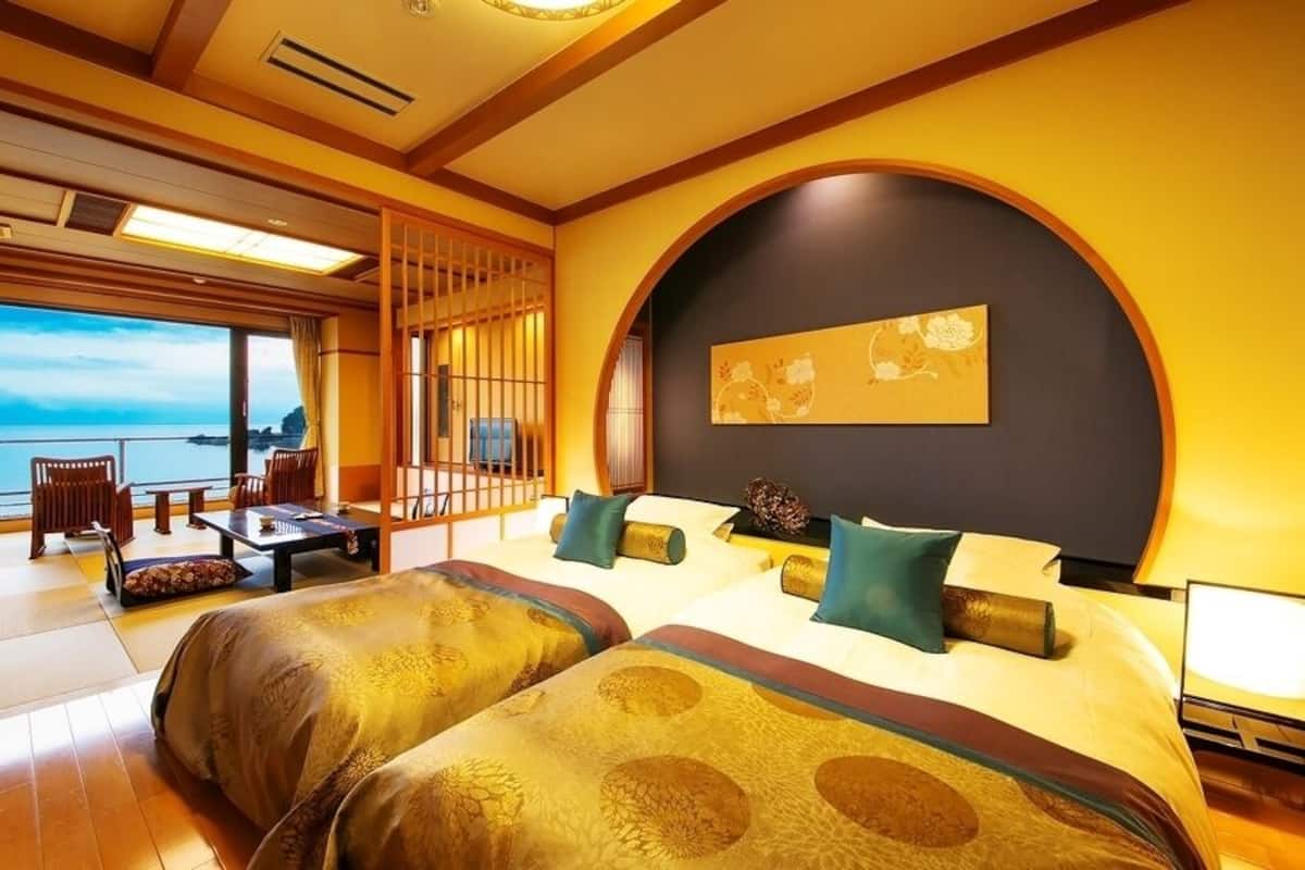 A room with a large bed, a desk, and a view of the sea.