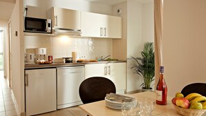 Una cocina moderna con armarios blancos, un microondas y un comedor con una mesa preparada para cuatro.