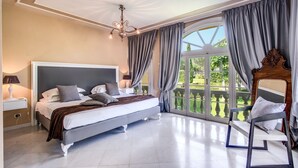 Ein geräumiges Schlafzimmer mit einem großen Bett, einem Sessel und Gartenblick durch ein großes Fenster.