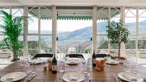 Ein Esstisch für sechs Personen mit Blick auf eine Berglandschaft durch große Fenster.
