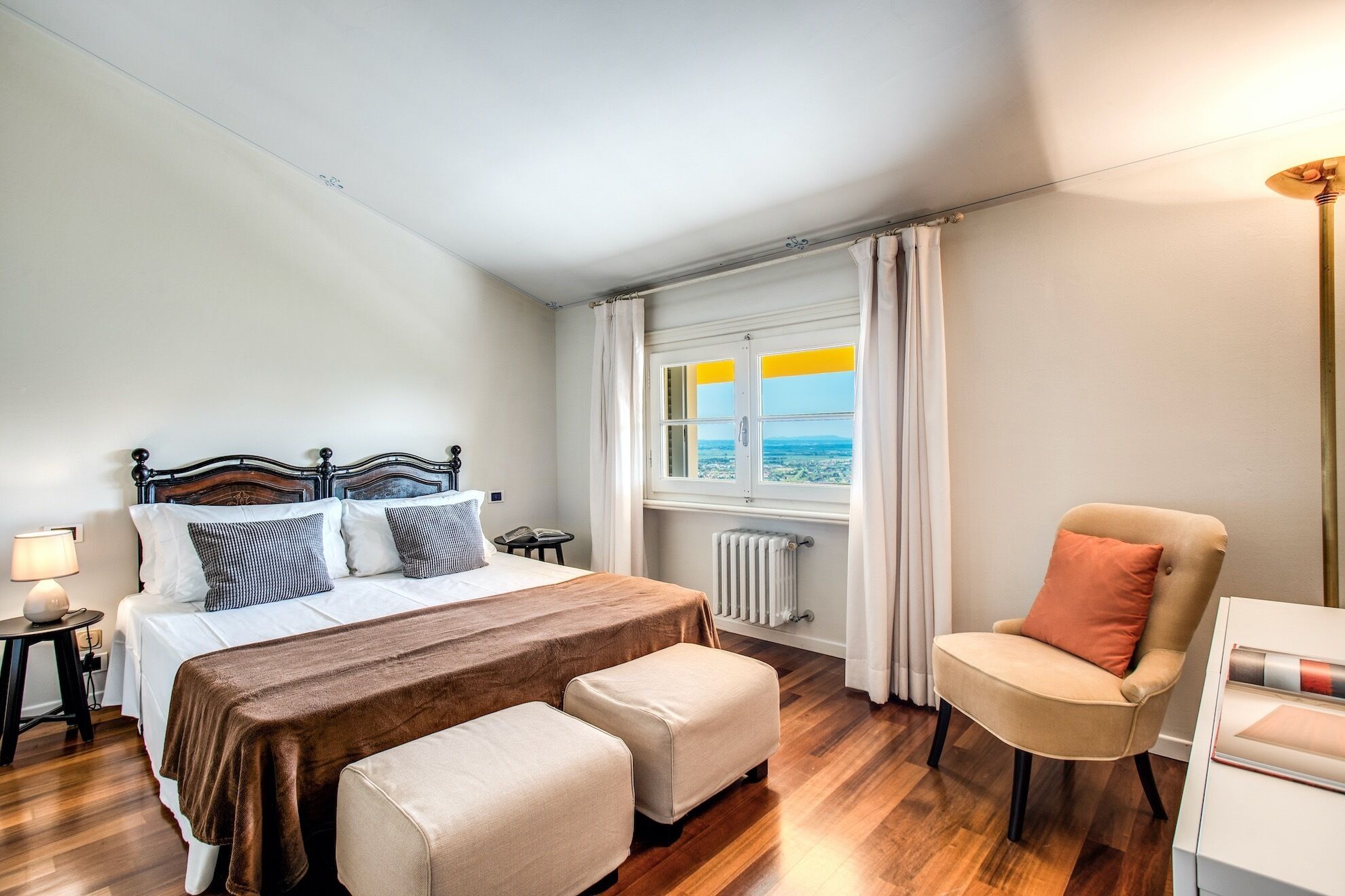 Une chambre à coucher avec un lit, une chaise, une table et une fenêtre avec des rideaux.