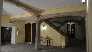 A stone-floored corridor with a staircase, a fire extinguisher, and a bench. - Hotel Barroco (Puebla)