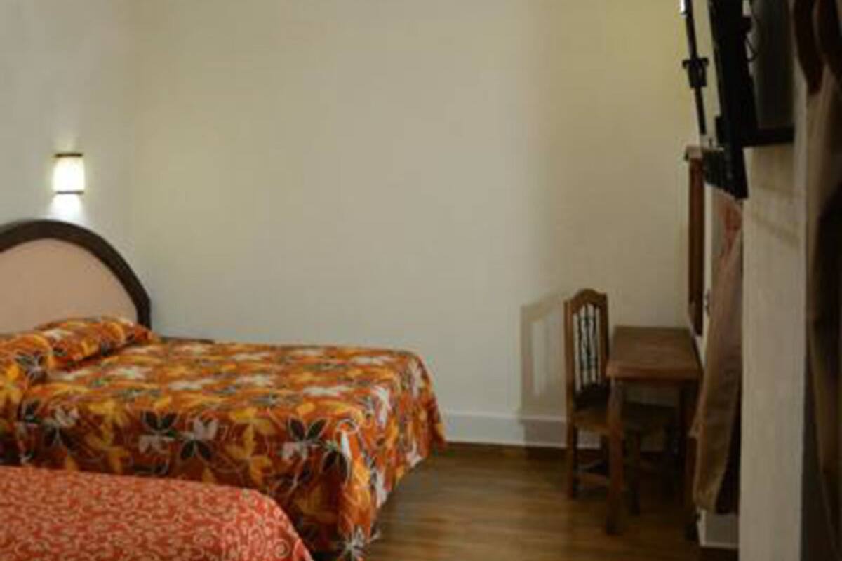 Une chambre avec deux lits, un plancher en bois, une chaise et un ventilateur de plafond.