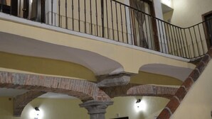 A multi-level interior with a stone staircase, multiple doors, and a balcony with a metal railing. - Hotel Barroco (Puebla)