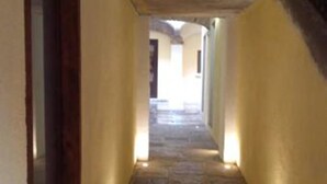 A stone-floored corridor with a wooden-framed window on the left, leading to a bright interior space. - Hotel Barroco (Puebla)