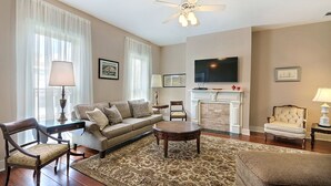 A living room with a sofa, armchairs, a coffee table, a fireplace, a television, and a patterned rug. - Heated Pool Access | 5*Clean | Flex Cancelation (Savannah)